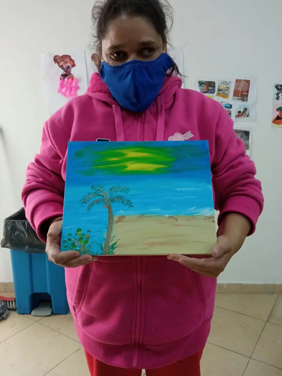 Pessoa atendida apresenta uma pintura feita durante atividade artística.